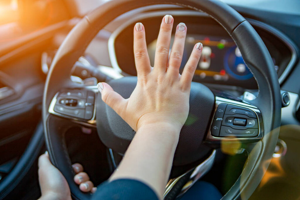 main féminine appuie sur le klaxon sur le volant d'une voiture moderne. pas de visage - Photo, image