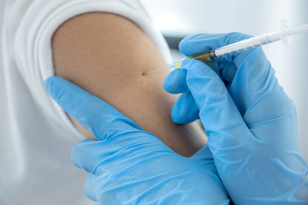 A mão do médico segurando uma seringa e estava prestes a vacinar um paciente na clínica para evitar a propagação do vírus. - Foto, Imagem