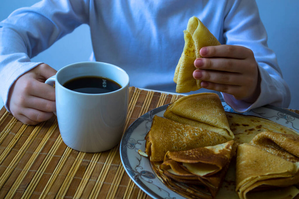 Carnival, the boy drinks coffee and eats pancakes. - Photo, Image