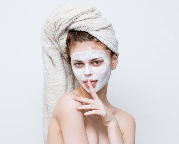 Çıplak omuzlu, başı havluyla cilt bakımı maskeli bir kadın. - Fotoğraf, Görsel