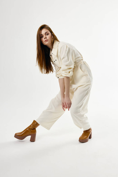 pretty woman in white jumpsuit leaned forward brown boots - Foto, imagen