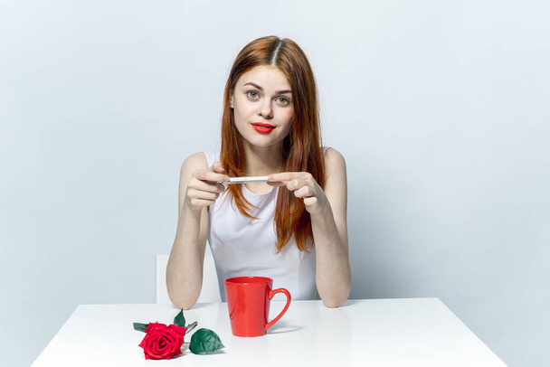 kobieta siedząca przy stole z czerwoną różą - Zdjęcie, obraz