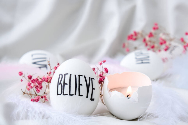 Easter DIY. Do it yourself. Trendy Easter eggs Composition. Easter message, Words drawn with pen. High Angle View Of Shells On Table. Believe. Candle in egg shell. Candle light Pastel colors. - Photo, Image