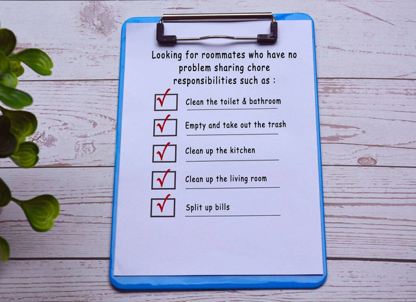 Texto em placa de clipe azul com caneta na mesa de madeira. Encontrar colega de quarto checklist - Foto, Imagem