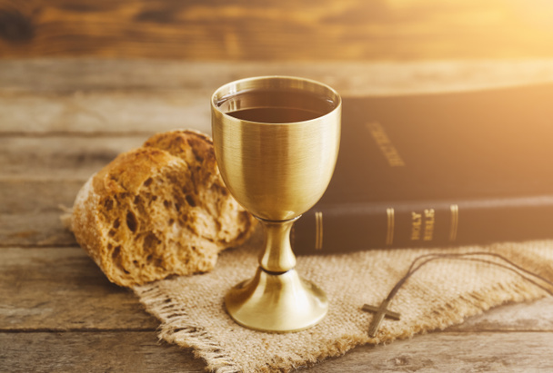 Chalice of wine with bread and Holy Bible on wooden background - Photo, Image