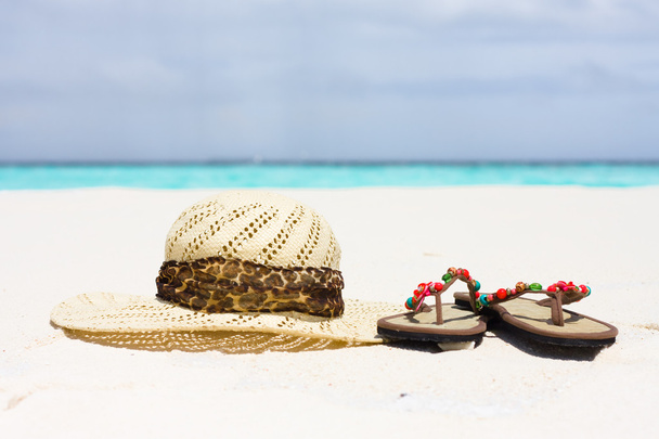 een hoed en sandalen liggen op zand - Foto, afbeelding