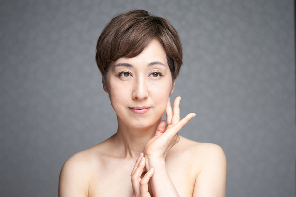 Японская женщина средних лет с руками на щеках - Фото, изображение
