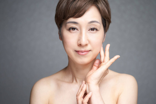 Японская женщина средних лет с руками на щеках - Фото, изображение