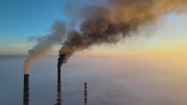 Повітряний вид на високі труби вугільної електростанції з чорним димом, що рухається вгору, забруднюючи атмосферу на заході сонця
. - Кадри, відео