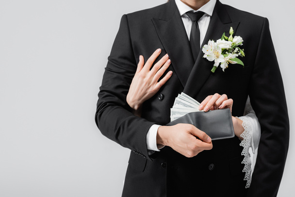 Περικοπή άποψη της νύφης αγκαλιάζει τον γαμπρό με χρήματα στο πορτοφόλι απομονώνονται σε γκρι  - Φωτογραφία, εικόνα