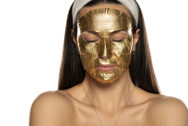 young woman posing with golden mask on her face on white background - Photo, Image