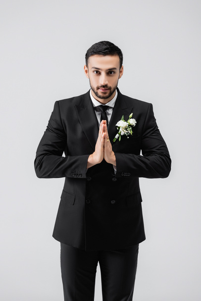 Arabian groom with praying hands looking at camera isolated on grey  - Photo, Image