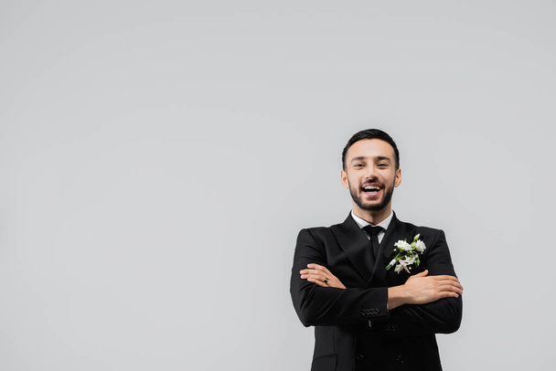 novio árabe positivo en traje mirando a la cámara aislada en gris  - Foto, Imagen