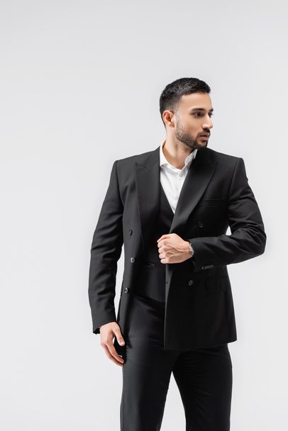 hombre musulmán de moda mirando hacia otro lado mientras camina aislado en gris - Foto, Imagen