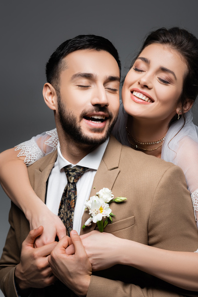 excité interracial jeunes mariés riant isolé sur gris - Photo, image