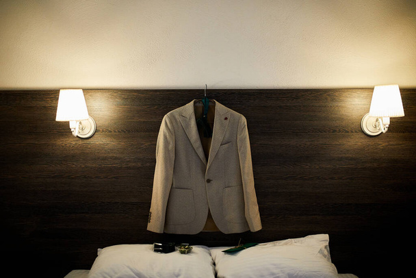 Cintre de vêtements de marié suspendu dans la chambre, Une veste homme sur cintre à la chambre d'hôtel, Le jour du mariage.  - Photo, image