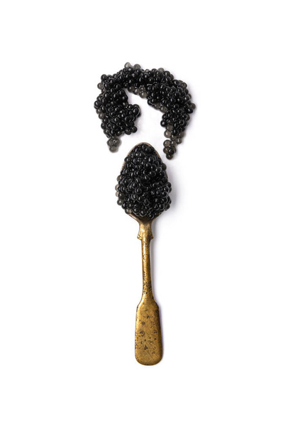 Vintage old spoon completely filled with black caviar isolated on a white background. top view - Photo, Image