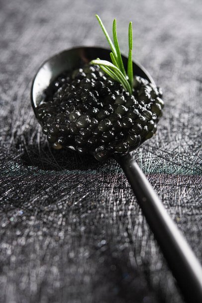Closeup of spoon with black caviar on a dark background. Seafood diet. rich food. - Photo, Image