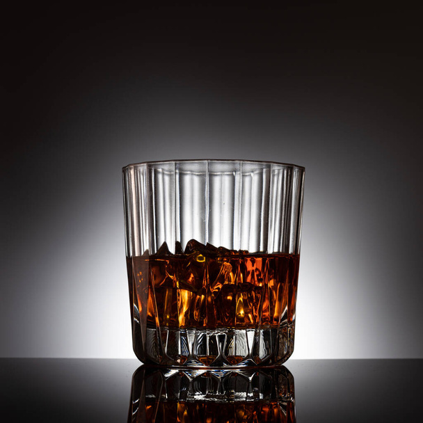 Cyrstalglas whisky met achtergrondverlichting en ijsblokjes - Foto, afbeelding