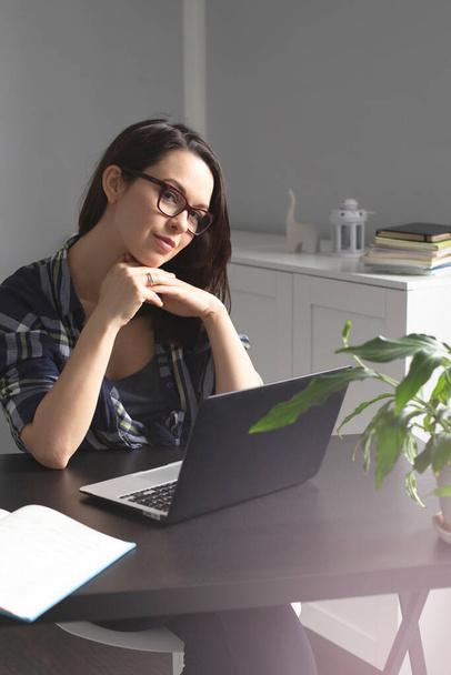 Mujer joven sonriente freelancer usando su portátil para estudiar y trabajar en línea desde casa disfrutando de un cómodo teletrabajo desde la oficina en casa. Autónomo y concepto freelance - Foto, Imagen