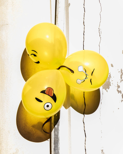 Globos divertidos y amarillos de emoji agrupados al sol para una fiesta callejera en Senigallia, Le Marche, Italia - Foto, Imagen