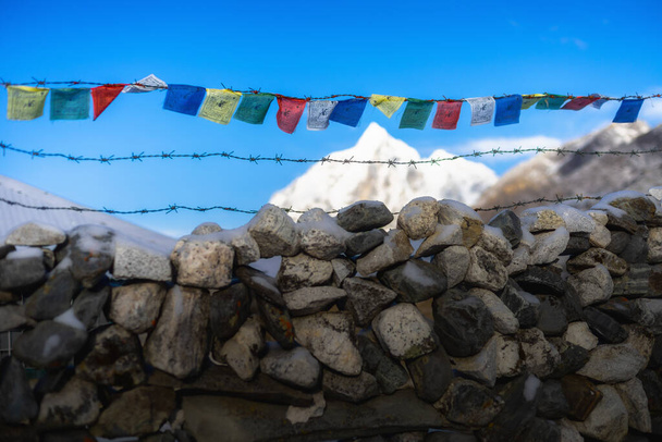 Drapeaux bouddhistes sur une clôture en pierre dans les montagnes himalayennes, Népal - Photo, image