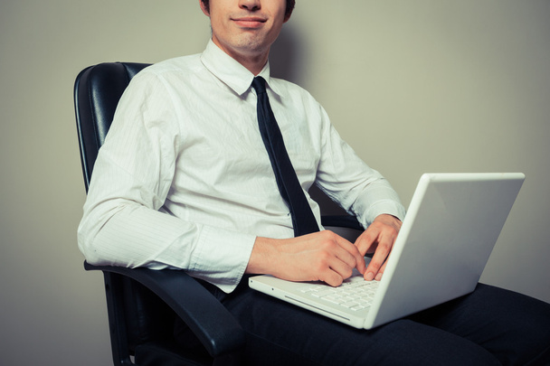 Businessman in office chair working on laptop - Foto, imagen