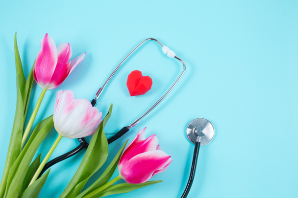 Bunch of pink tulips and stethoscope on blue background. - Photo, Image