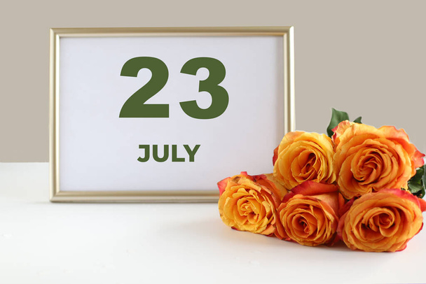 kuukauden päivä 23 Heinäkuu kalenteri valokuvakehys ja keltainen ruusu valkoisella pöydällä. - Valokuva, kuva