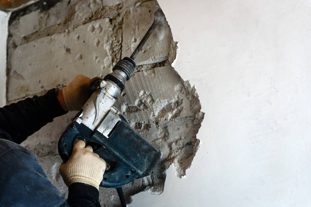 Εργαζόμενος με σφυρί κατεδάφισης αφαίρεση σοβά από τον τοίχο. - Φωτογραφία, εικόνα