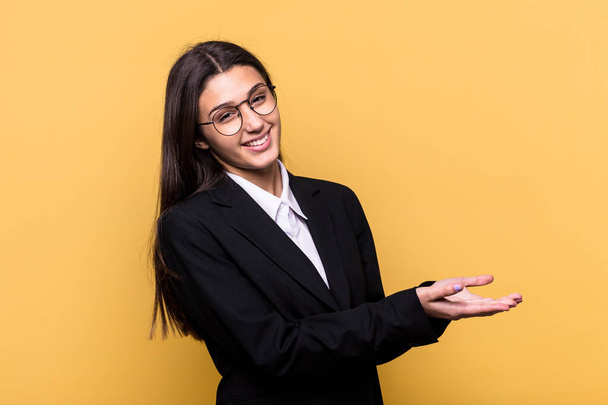 Young Indian business woman isolated on yellow background holding a copy space on a palm. - Photo, image