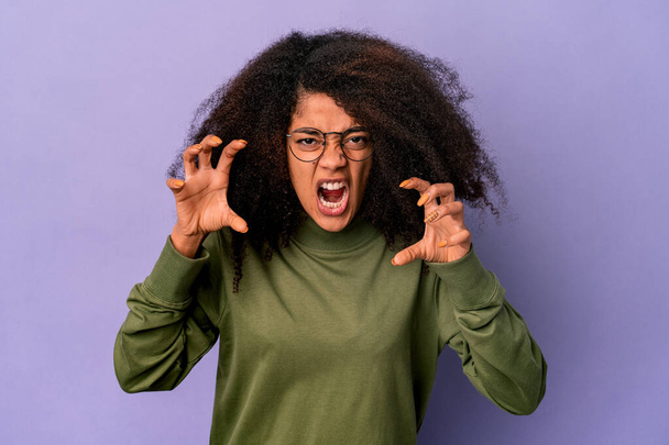 Young african american curly woman isolated on purple background showing claws imitating a cat, aggressive gesture. - Photo, Image