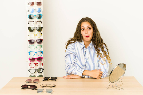 Junge kaukasische Frau versucht Brille isoliert Achselzucken und offene Augen verwirrt. - Foto, Bild