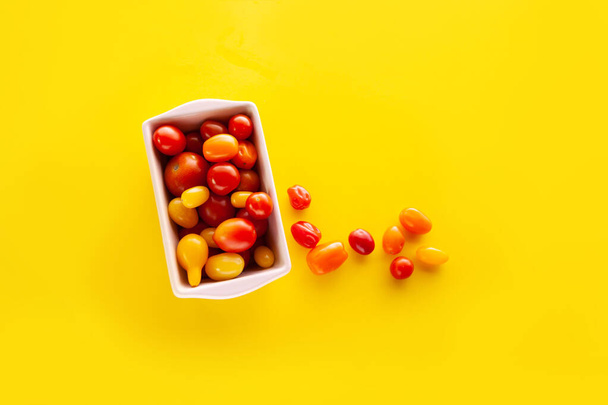 Boîte carrée en bois avec tomates cerises fraîches sur fond jaune - Photo, image