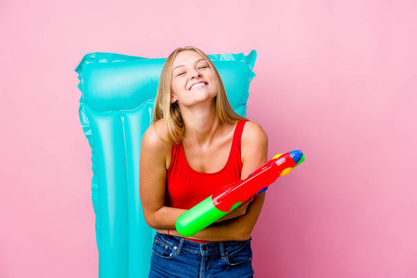 Giovane donna russa che gioca con una pistola ad acqua con un materasso ad aria ridere e divertirsi. - Foto, immagini