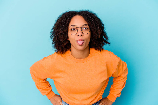 Young african american mixed race woman isolated funny and friendly sticking out tongue. - Photo, Image