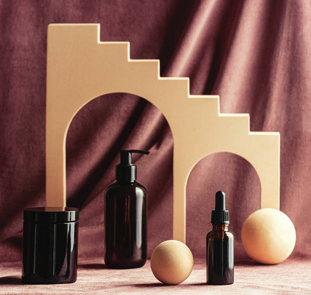 presentazione di contenitori cosmetici scuri accanto a forme geometriche dorate  - Foto, immagini