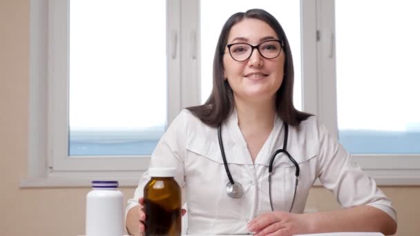 Alegre médico mujer muestra botellas con medicamentos a la cámara - Metraje, vídeo