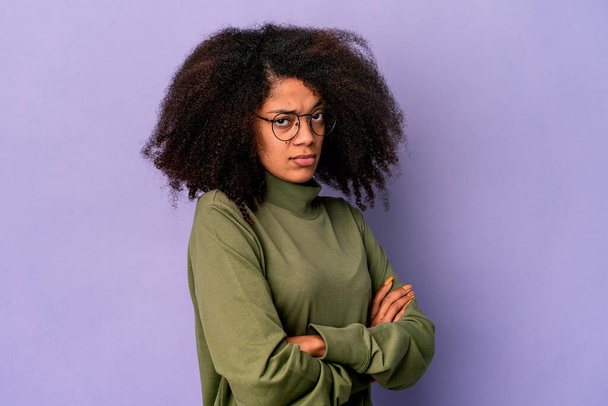 Young african american curly woman isolated on purple background suspicious, uncertain, examining you. - Φωτογραφία, εικόνα