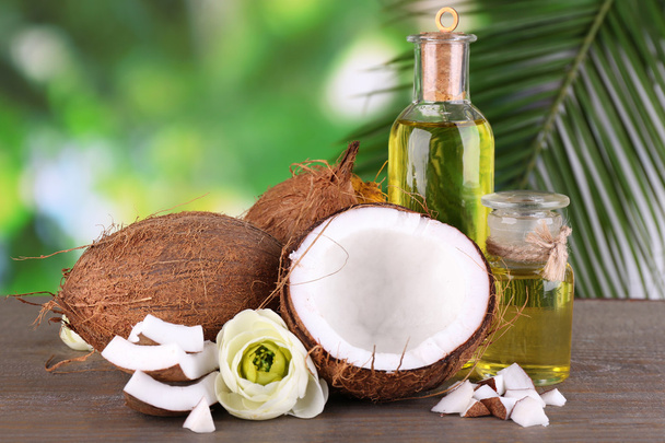 Coconuts and coconut oil on wooden table, on nature background - Foto, Bild