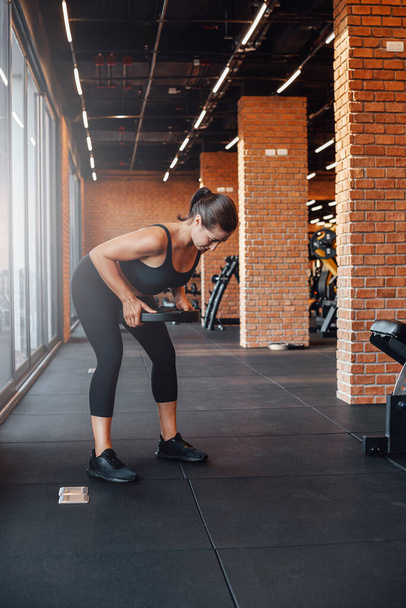 Γυναικεία bodybuilder τρένα ανύψωσης μια αλτήρα στο σύγχρονο γυμναστήριο - Φωτογραφία, εικόνα