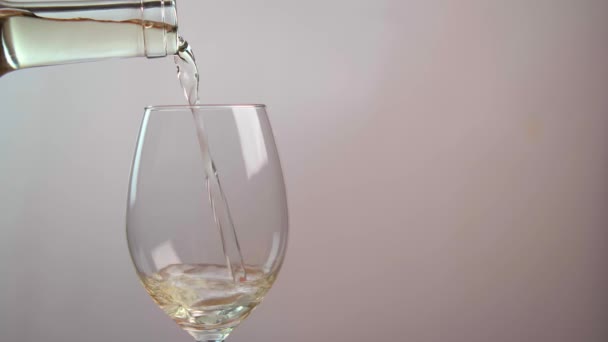 Primer plano del vino blanco que se vierte de una botella en un vaso de vidrio, aislado sobre un fondo blanco. Concepto de alcohol - Imágenes, Vídeo