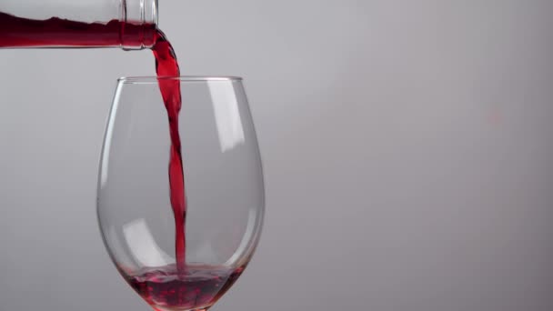 Kırmızı şarap şişeden cam bardağa dökülüyor, beyaz arka planda izole edilmiş. Alkol kavramı - Video, Çekim