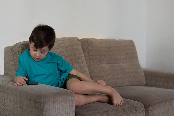 kid concentrated with mobile device, playing online game, watching cartoons or video - Photo, Image