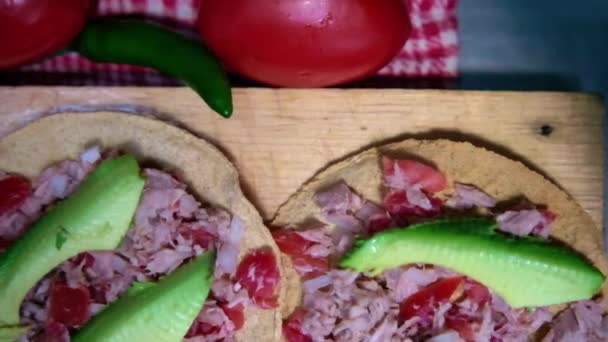 Traditionele Mexicaanse tonijn tostadas op houten plank en omgeven door groenten - Video
