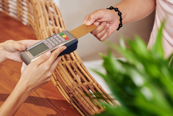 Ruce hotelového recepčního držícího platební terminál, když hotelový host kradl kreditní kartu - Fotografie, Obrázek