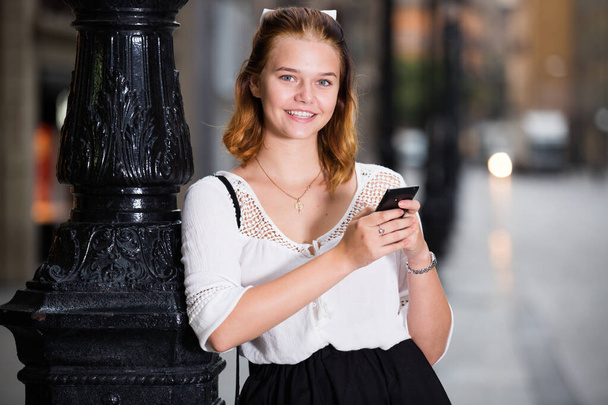 Portrait of smiling girl using mobile phone - Фото, изображение