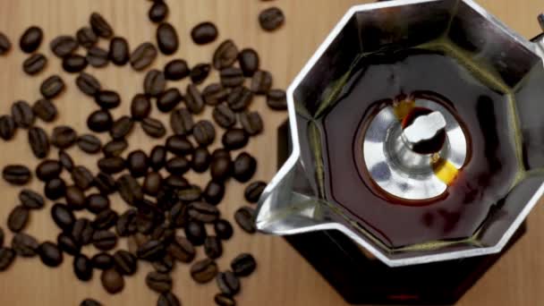 Het proces van het maken van koffie in Italiaanse moka pot. Geiser koffiezetapparaat. Op de achtergrond zijn koffiebonen. - Video