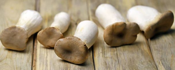  Rauwe eringi champignons op een houten ondergrond. - Foto, afbeelding