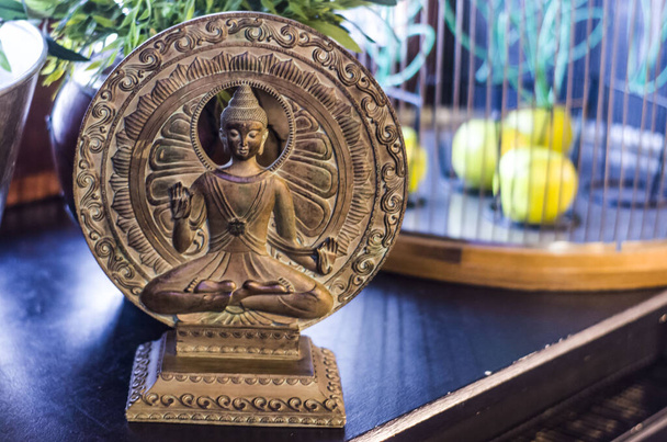 Buddha figurine on a background of bronze circles. Sacral figurine in the interior. - Photo, Image
